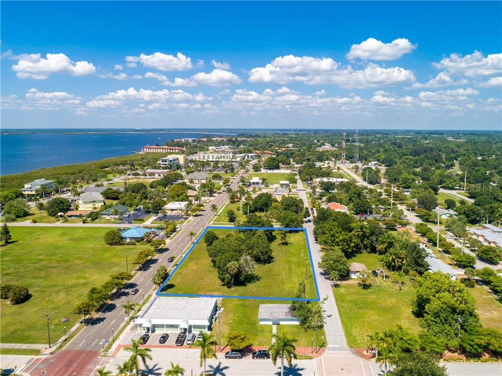 An aerial view shows a vacant rectangular lot outlined in blue near a coastal road — 427,407, 417, 425 E OLYMPIA AVENUE, PUNTA GORDA, FL