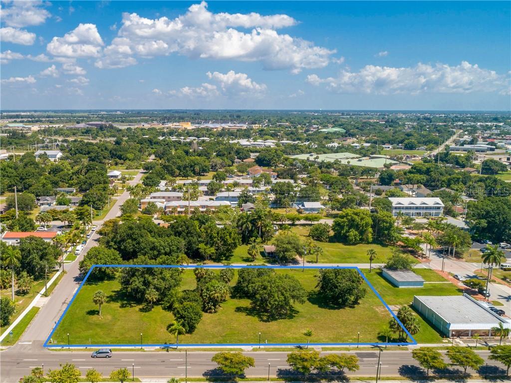 An aerial view shows a vacant, grassy lot outlined in blue near a paved road — 427,407, 417, 425 E OLYMPIA AVENUE, PUNTA GORDA, FL