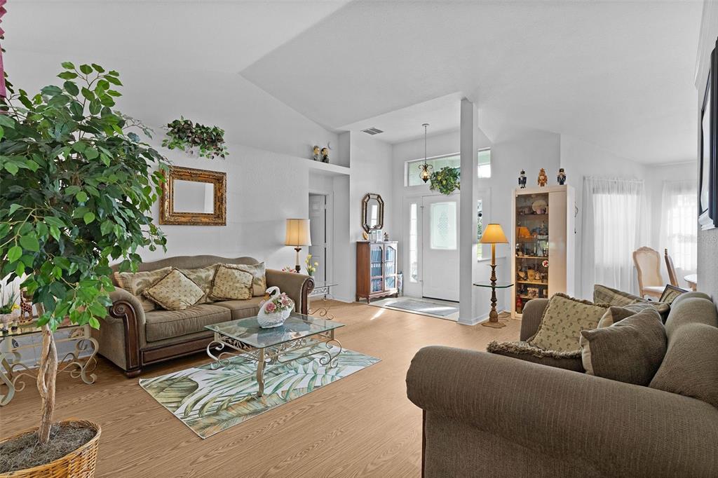A living room features light wood-look flooring, two brown sofas, and a glass-topped coffee table — 17566 SE 112TH AVENUE, SUMMERFIELD, FL