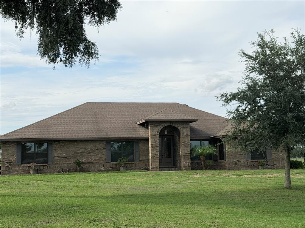 A single-story brick house with a hip roof and an arched entryway sits on a lawn — 6102 DOWNING STREET, DOVER, FL