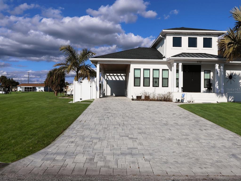 A white two-story house features a paved driveway, a carport, and a dark front door — 112 LELAND STREET SE, PORT CHARLOTTE, FL