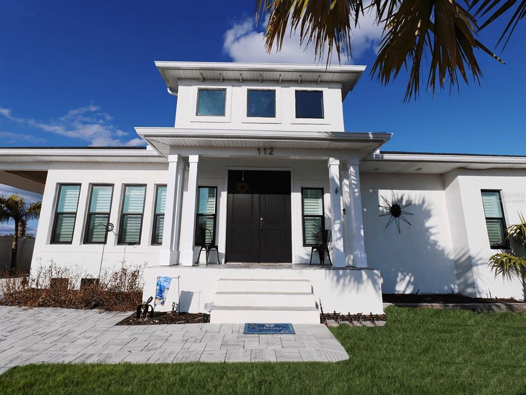A white single-story house with a black double front door and a central roof monitor — 112 LELAND STREET SE, PORT CHARLOTTE, FL