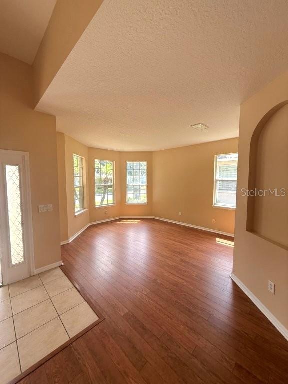 An empty room features wood-look flooring, beige walls, and a bay window — 1102 MAGNOLIA BLOSSOM COURT, APOPKA, FL