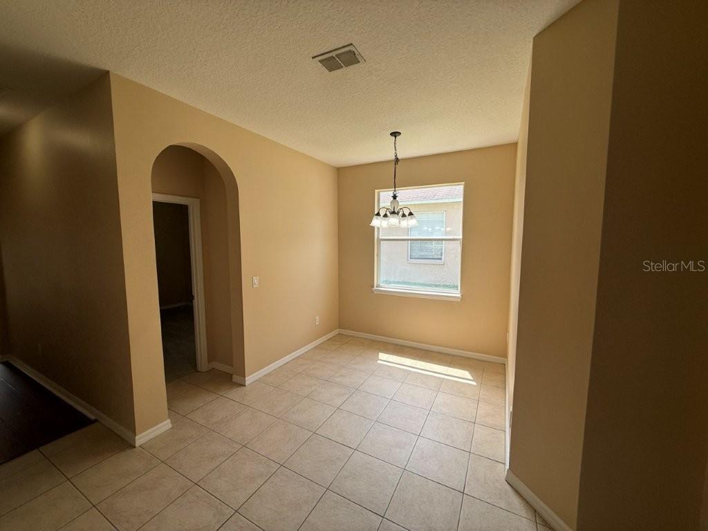 A dining area features beige walls, tile flooring, a chandelier, and an arched doorway — 1102 MAGNOLIA BLOSSOM COURT, APOPKA, FL