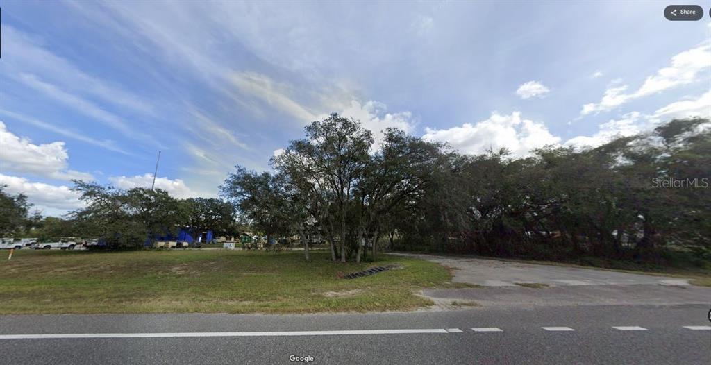 A grassy lot with several large trees and a paved area along a road — N/A, POLK CITY, FL