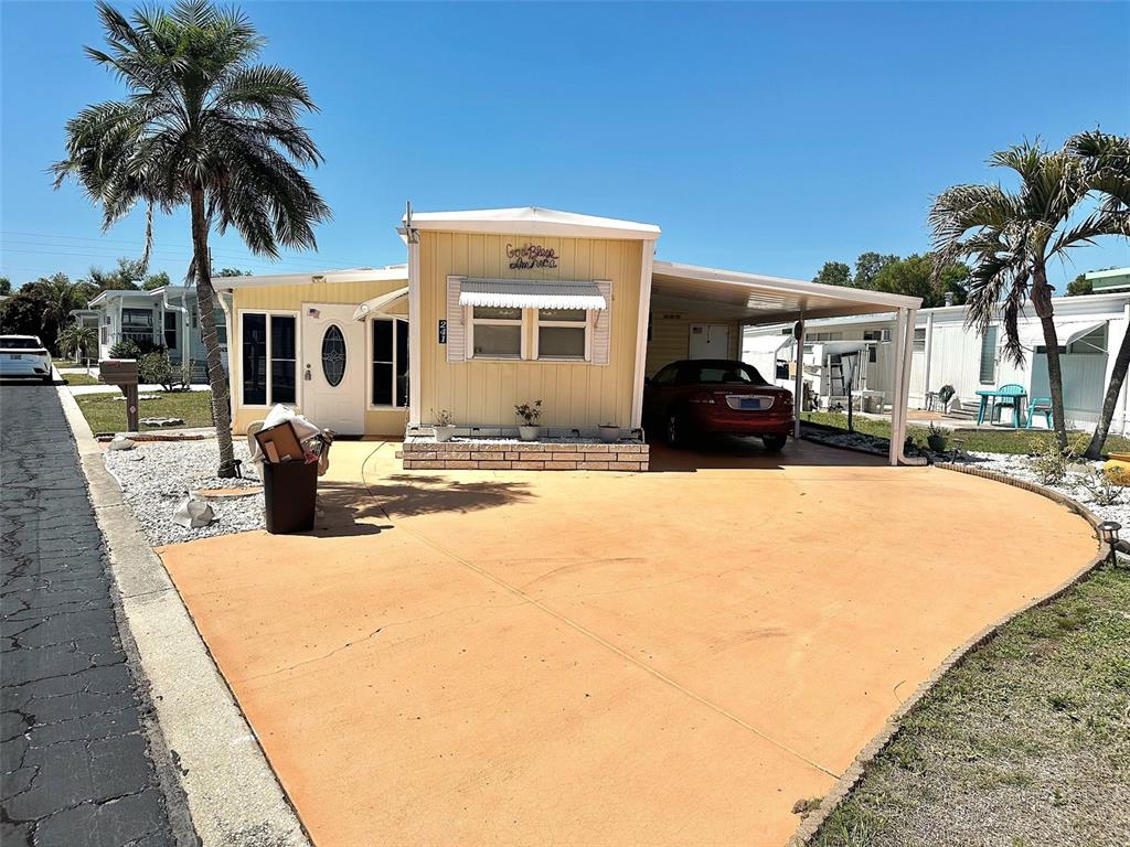 A yellow mobile home with a carport, palm trees, and a paved driveway — 8300 SEMINOLE BOULEVARD UNIT 241, SEMINOLE, FL