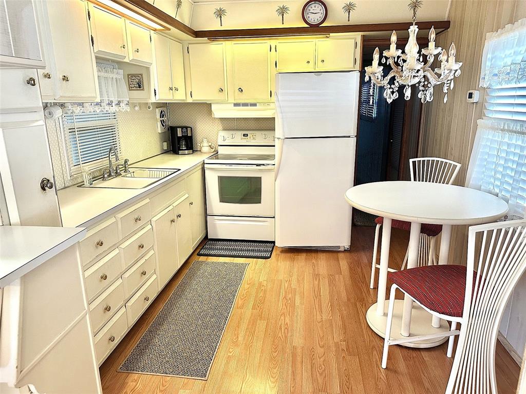 A kitchen features light-colored cabinetry, white appliances, a dining table, and wood-look flooring — 8300 SEMINOLE BOULEVARD UNIT 241, SEMINOLE, FL