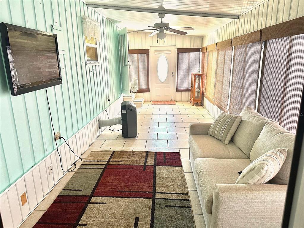 A sunroom features light blue walls, tile flooring, a sofa, and a portable air conditioner — 8300 SEMINOLE BOULEVARD UNIT 241, SEMINOLE, FL