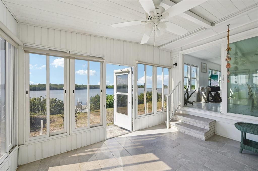 A sunroom with tile flooring, a ceiling fan, and large windows overlooking a waterfront view — 156 MARTINIQUE ROAD, NORTH PORT, FL