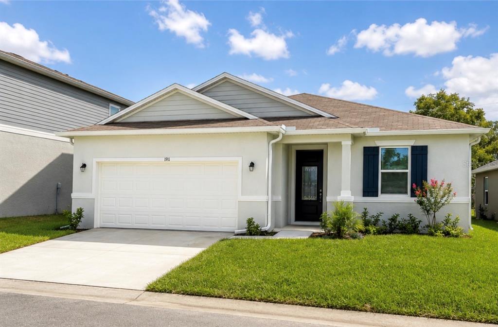 A single-story house with a white garage, light-colored stucco exterior, and dark blue window shutters — 1911 MAPLE PLUM COURT, SANFORD, FL