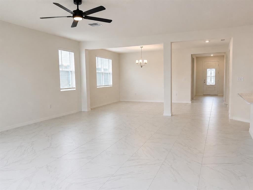 An open-concept living and dining area features white marble-look tile flooring and a ceiling fan — 1911 MAPLE PLUM COURT, SANFORD, FL