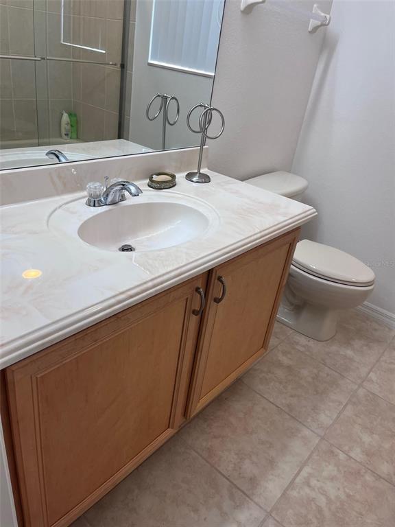 A bathroom features a light-colored vanity with a single sink, wood cabinets, and a toilet — 2931 BENTON LANE, KISSIMMEE, FL