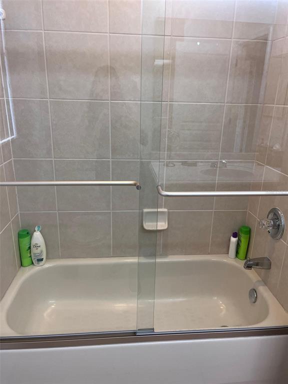 A bathtub with a sliding glass door and tiled walls in a bathroom — 2931 BENTON LANE, KISSIMMEE, FL
