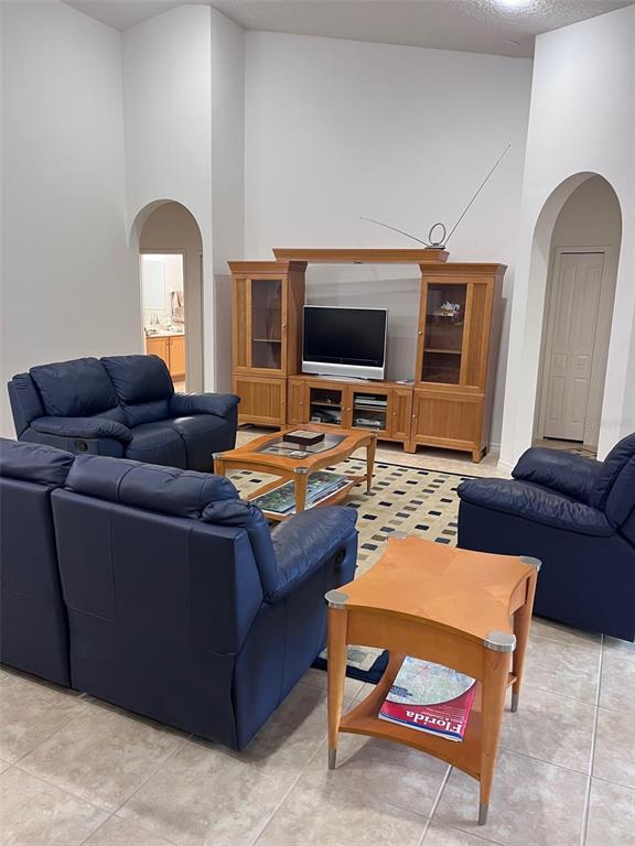A living room features blue leather furniture, a wooden entertainment center, and tile flooring — 2931 BENTON LANE, KISSIMMEE, FL