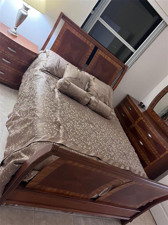 A bedroom features a wooden bed frame, matching nightstand, and dresser with a patterned comforter — 2931 BENTON LANE, KISSIMMEE, FL