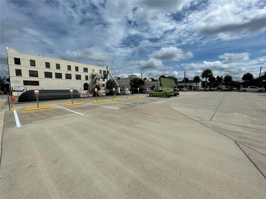 A large, empty concrete parking lot sits in front of a multi-story white building — 113 S WOODLAND BOULEVARD, DELAND, FL