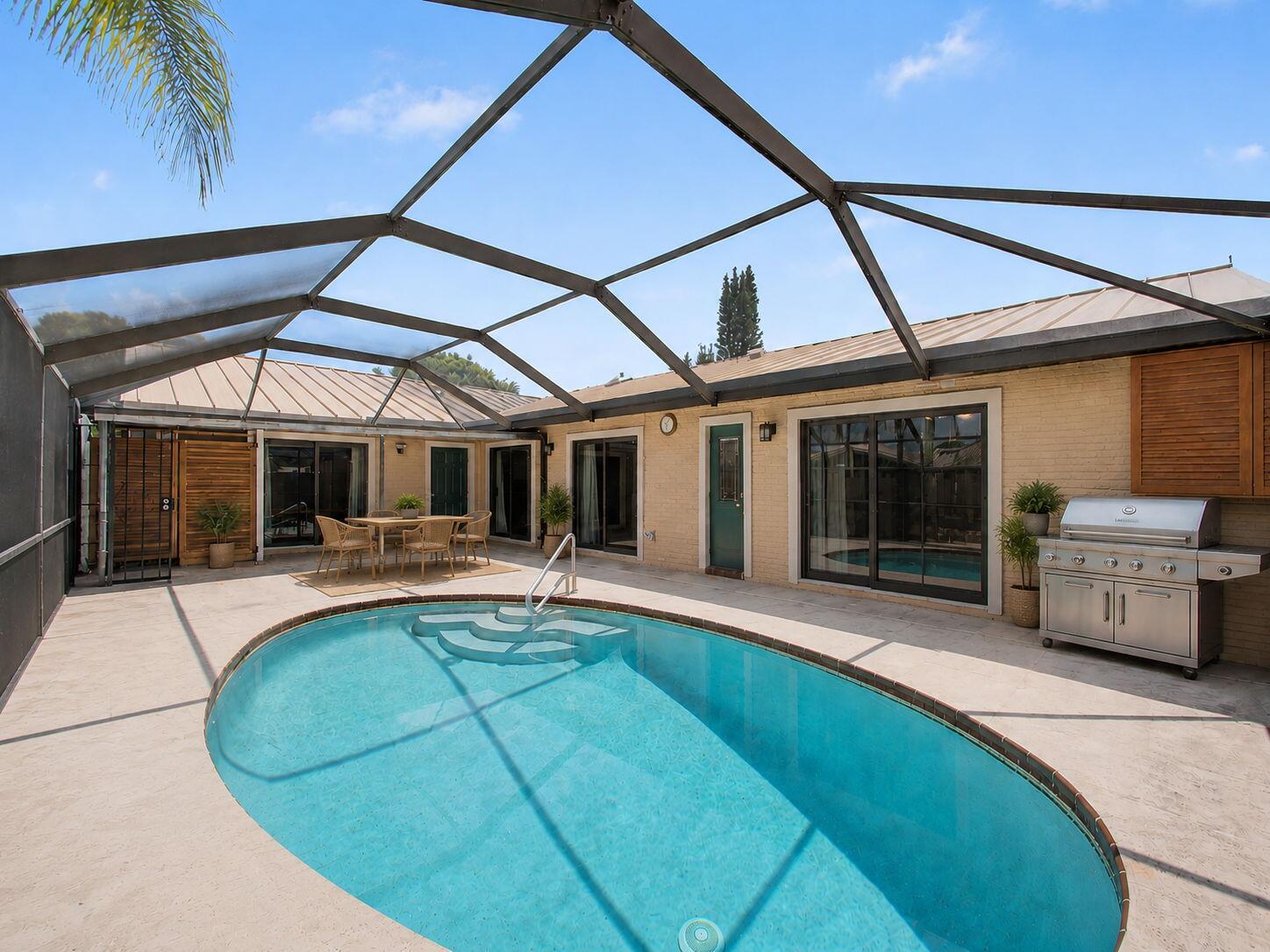 A living room with a vaulted ceiling, white sofa, two armchairs, and a sliding glass door — 5385 Eagle Lake Drive, Palm Beach Gardens FL 33418, PALM BEACH GARDENS, FL
