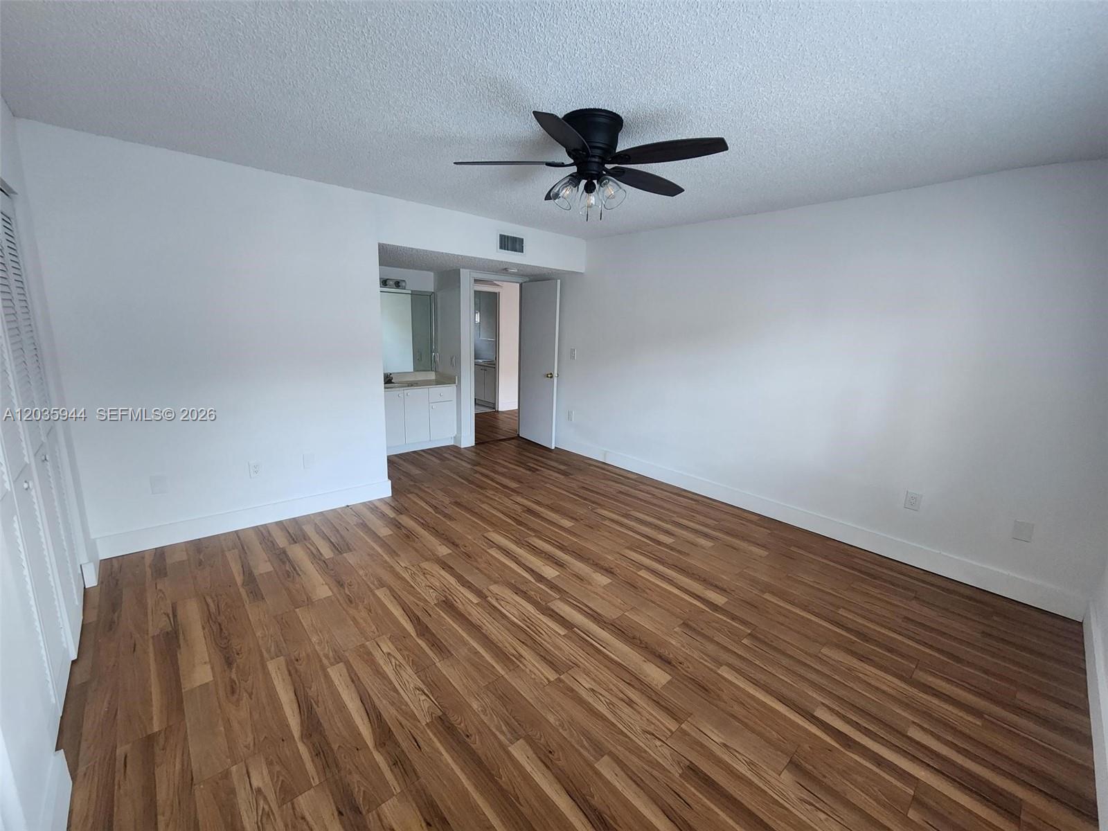An empty bedroom features white walls, wood-look flooring, and a ceiling fan — 10019 W Okeechobee Rd # 102, Hialeah Gardens FL 33016, HIALEAH GARDENS, FL