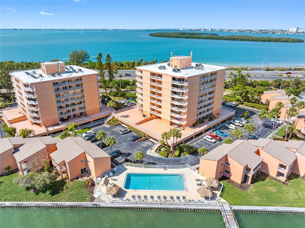 An aerial view shows two multi-story apartment buildings, a swimming pool, and a waterfront dock — 7430 SUNSHINE SKYWAY LANE S UNIT 406, ST PETERSBURG, FL