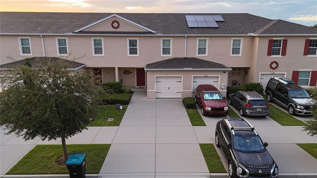 An exterior view of a multi-unit townhouse complex with driveways and parked cars — 12418 BOWES BRANCH ROAD, ORLANDO, FL