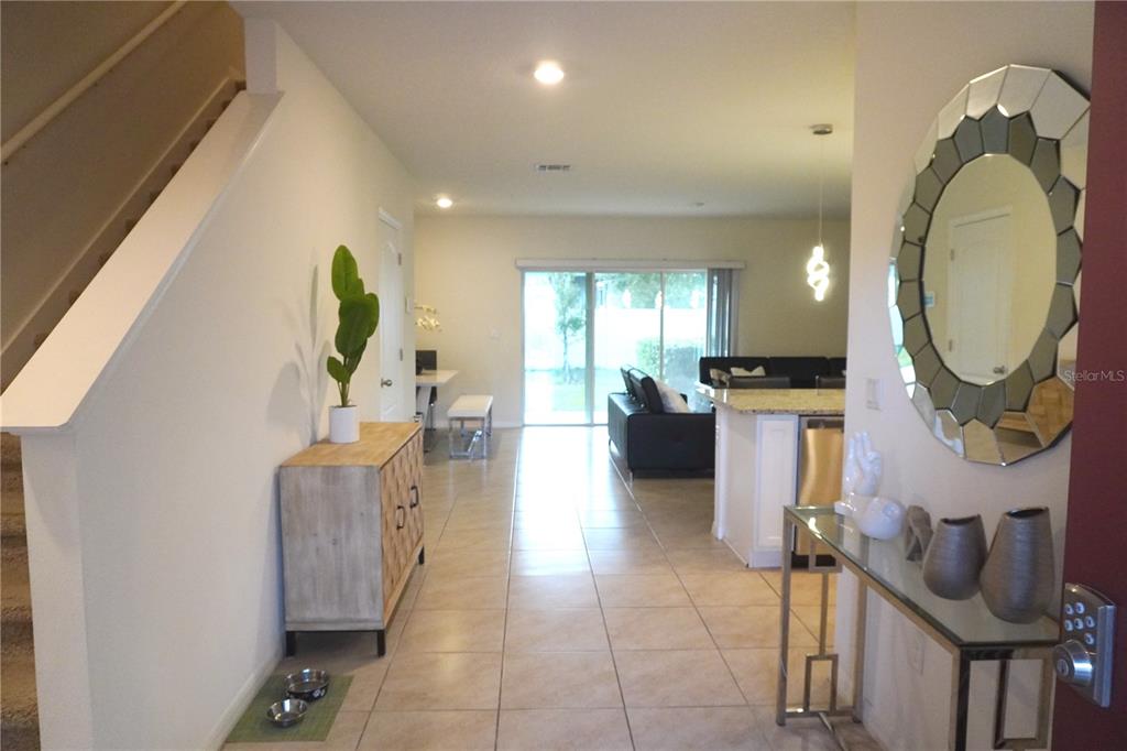 An entryway leads into an open-concept living area with tile floors and a kitchen island — 12418 BOWES BRANCH ROAD, ORLANDO, FL