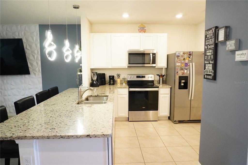 A kitchen features white cabinets, granite countertops, stainless steel appliances, and a large island — 12418 BOWES BRANCH ROAD, ORLANDO, FL