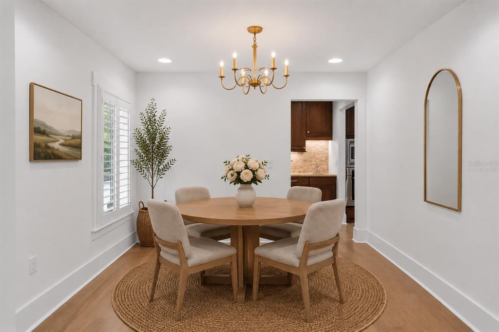 A dining room features a round wooden table, four upholstered chairs, and a gold chandelier — 1265 ARLINGTON PL, WINTER PARK, FL