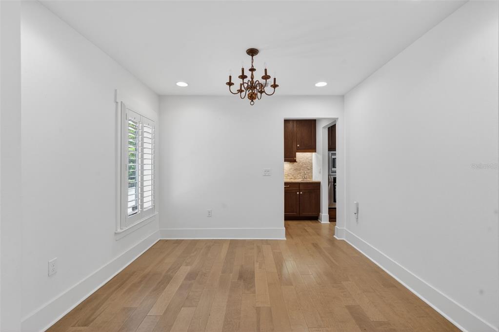 An empty dining room with hardwood floors, a chandelier, and a view into a kitchen — 1265 ARLINGTON PL, WINTER PARK, FL