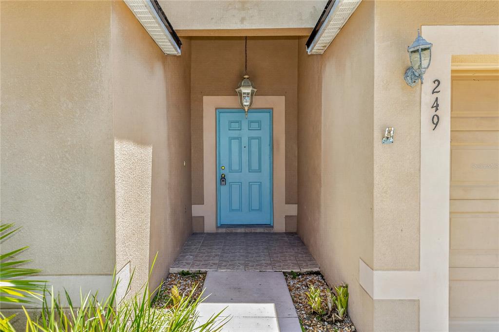 The exterior entrance features a light blue front door and a tiled porch area — 249 CURTIS AVENUE, GROVELAND, FL
