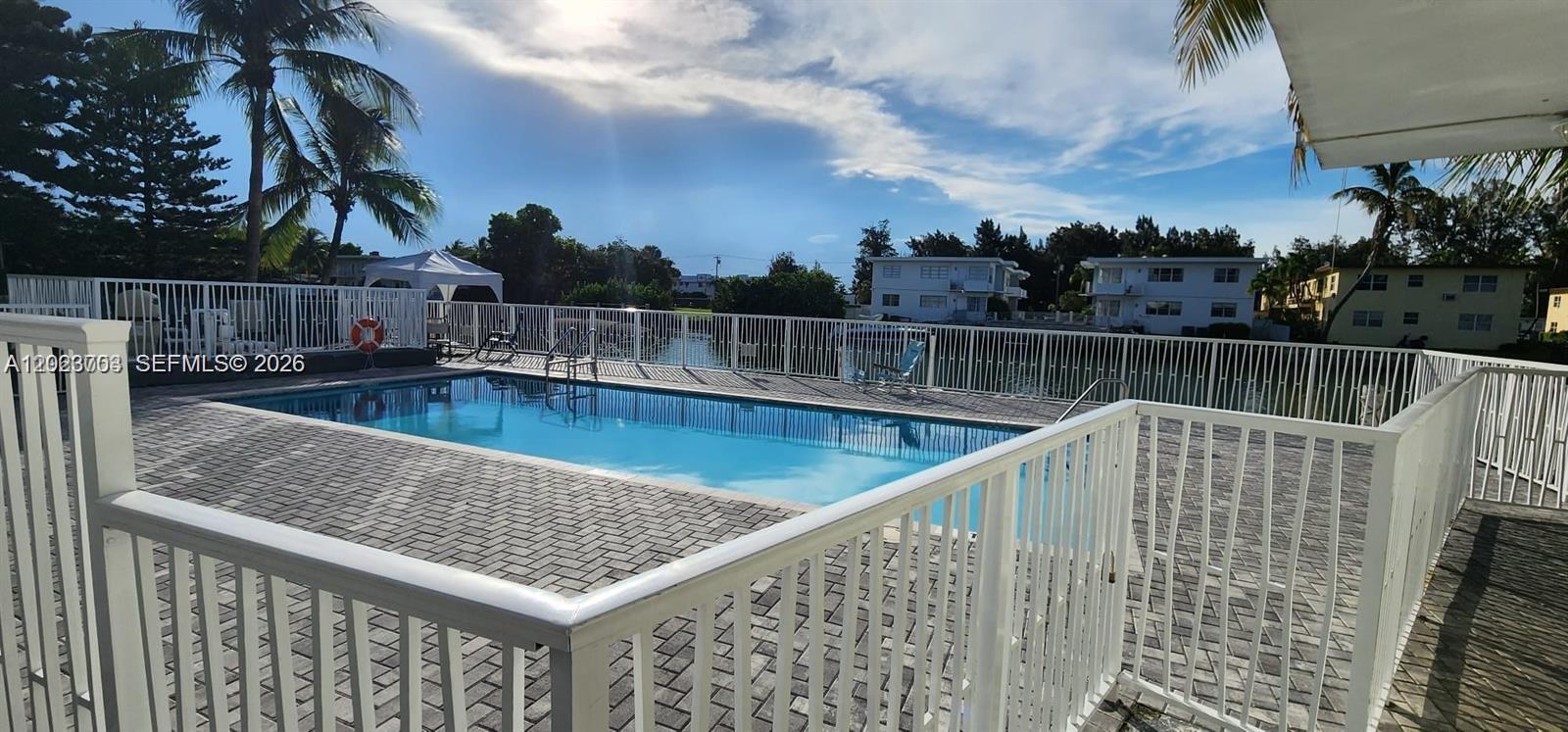 A rectangular swimming pool is surrounded by a white fence and paved deck — 1233 Marseille Dr # 5, Miami Beach FL 33141, MIAMI BEACH, FL