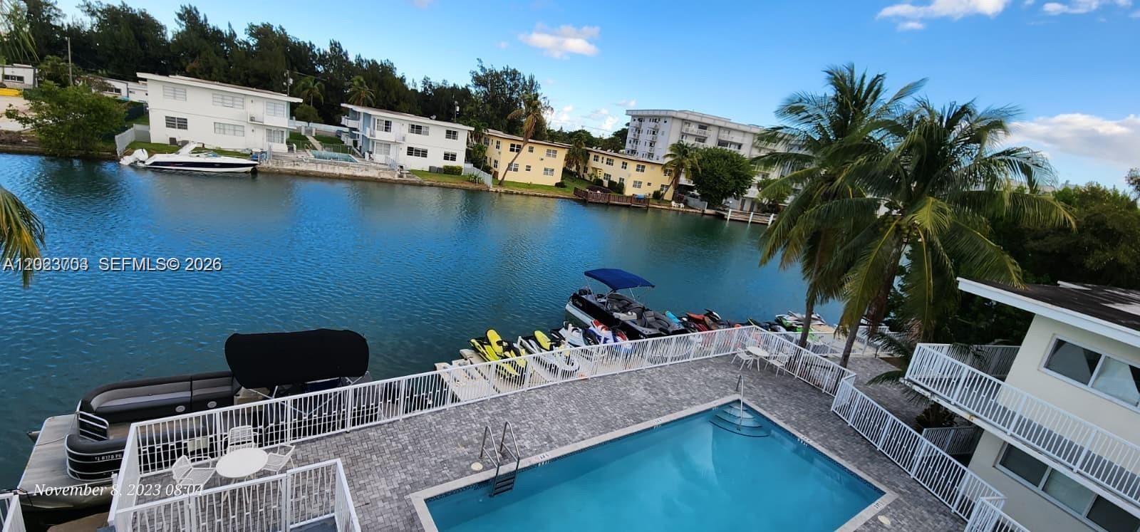 An elevated view shows a swimming pool, a patio, and a canal with docked boats — 1233 Marseille Dr # 5, Miami Beach FL 33141, MIAMI BEACH, FL
