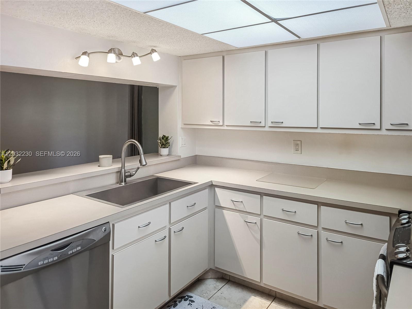 A kitchen features white flat-panel cabinets, light countertops, a stainless steel sink, and recessed lighting — 9531 Seagrape Dr # 108, Davie FL 33324, DAVIE, FL