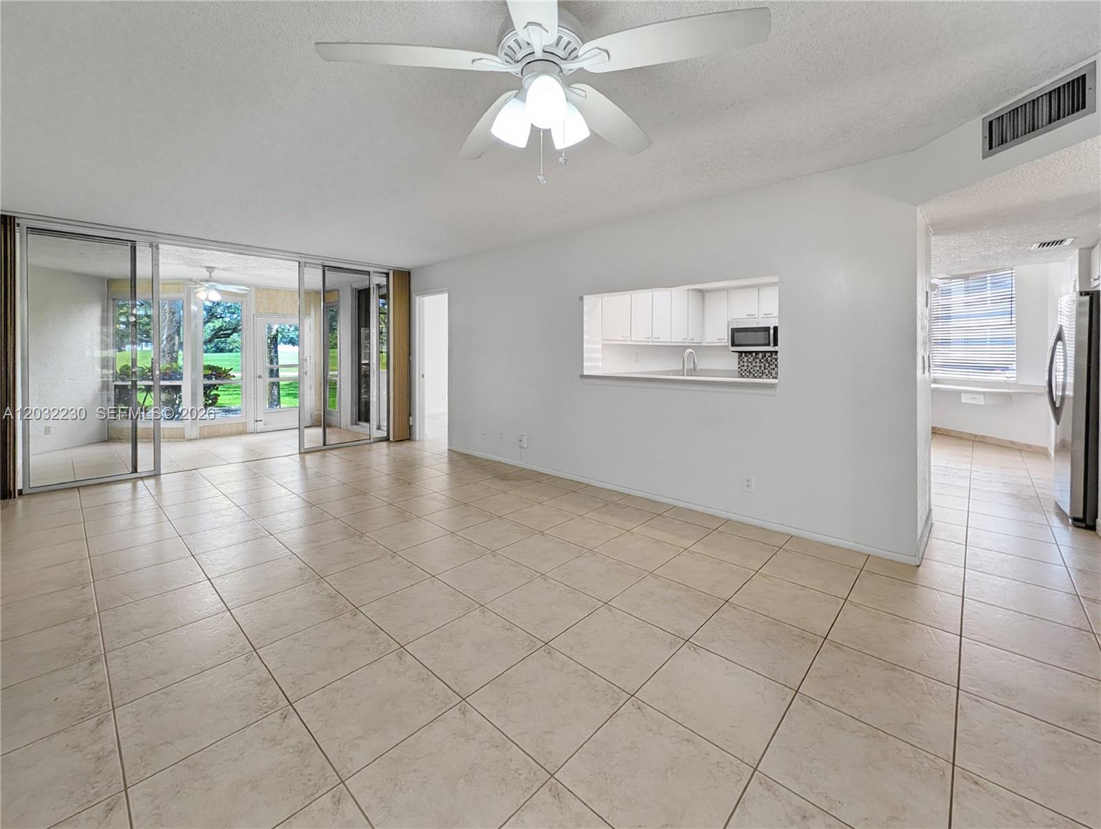 An open living area with tile floors, a ceiling fan, and a kitchen pass-through window — 9531 Seagrape Dr # 108, Davie FL 33324, DAVIE, FL