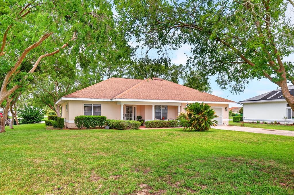 A single-story house with a tan exterior, a brown shingled roof, and a grassy front yard — 17520 SE 112TH AVENUE, SUMMERFIELD, FL