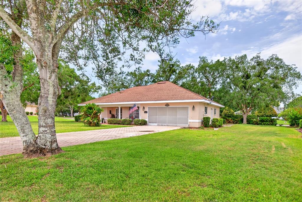 A single-story house with a tan exterior, a brown roof, and a paved driveway — 17520 SE 112TH AVENUE, SUMMERFIELD, FL