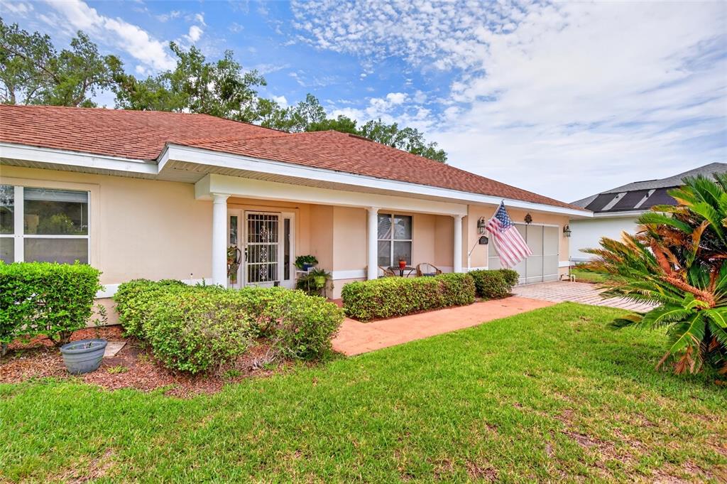 A single-story house with a tan exterior, a red roof, and a covered front porch — 17520 SE 112TH AVENUE, SUMMERFIELD, FL