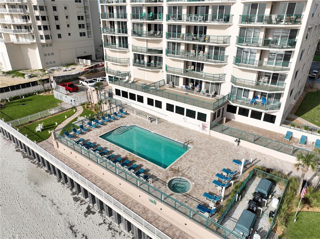 An aerial view of a beachfront condominium building featuring a swimming pool and hot tub — 3315 S ATLANTIC AVENUE UNIT 806, DAYTONA BEACH SHORES, FL