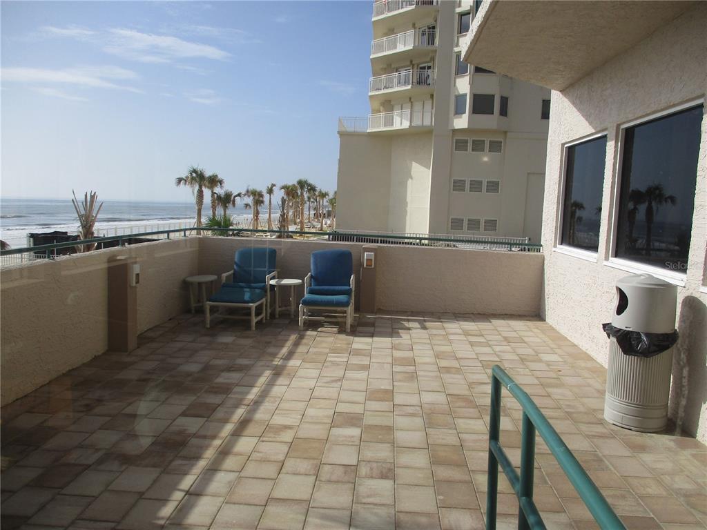 A tiled balcony overlooks the ocean with two blue chairs and a trash receptacle — 3315 S ATLANTIC AVENUE UNIT 806, DAYTONA BEACH SHORES, FL
