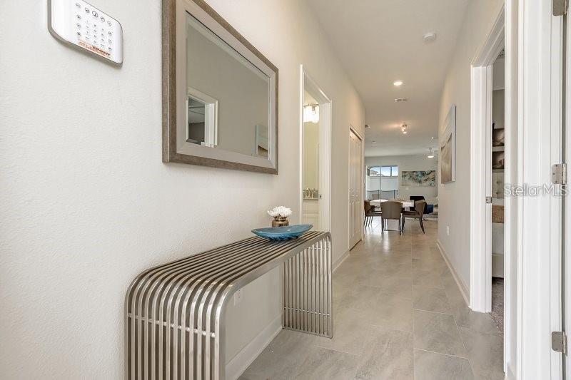 A hallway with light tile flooring, a metal console table, and a wall-mounted mirror — 1585 SANDBAGGER DRIVE, CHAMPIONS GATE, FL