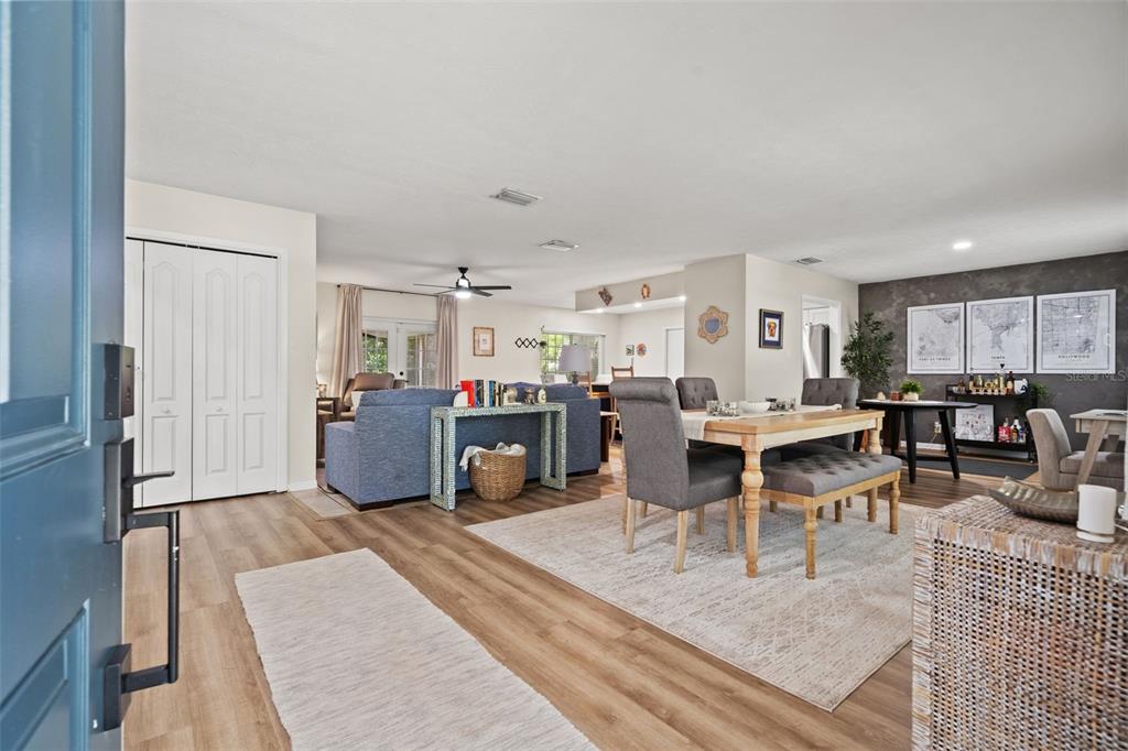 An open-concept living and dining area features wood-look flooring, a blue sofa, and a dining table — 15521 WETSTONE DRIVE, TAMPA, FL