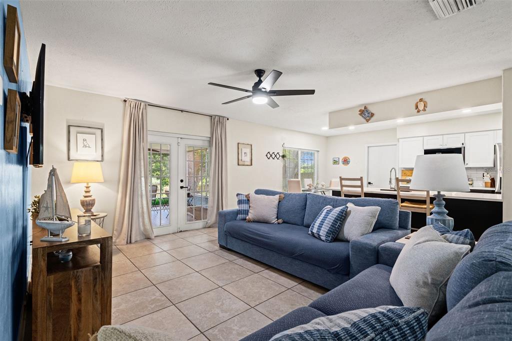 A living room features blue sofas, tile flooring, a ceiling fan, and an open kitchen — 15521 WETSTONE DRIVE, TAMPA, FL