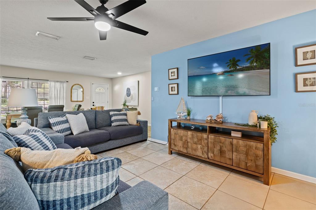 A living room features a blue sofa, a wooden media console, and a wall-mounted television — 15521 WETSTONE DRIVE, TAMPA, FL