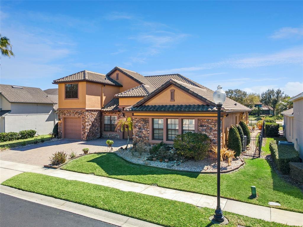 A two-story house with a stone facade, tile roof, and a paved driveway — 6473 EVERINGHAM LANE, SANFORD, FL