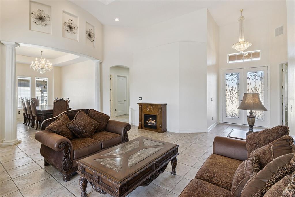 A living room with tile floors, brown furniture, a fireplace, and an adjacent dining area — 6473 EVERINGHAM LANE, SANFORD, FL