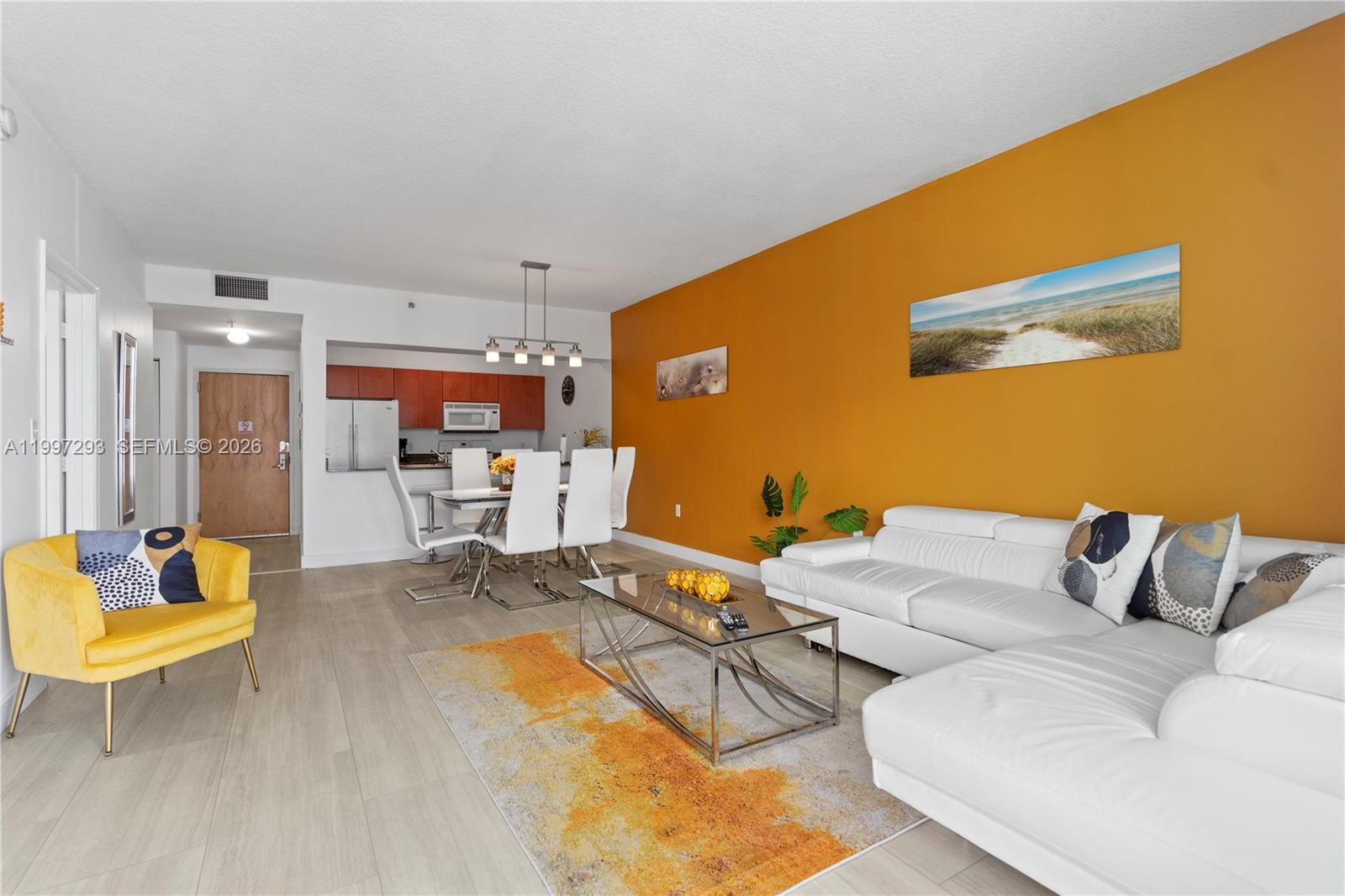 A living room features a white sectional sofa, yellow armchair, and an orange accent wall — 1200 Brickell Bay Dr # 4218, Miami FL 33131, MIAMI, FL