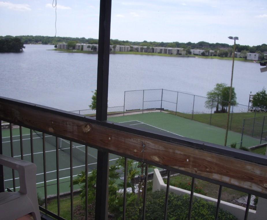 A balcony view overlooks a tennis court and a lake with distant buildings — 618 ORANGE DRIVE UNIT 212, ALTAMONTE SPRINGS, FL
