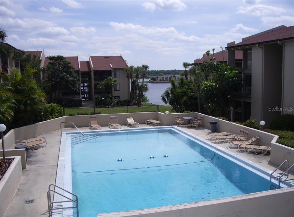 An outdoor swimming pool surrounded by lounge chairs with a view of a lake — 618 ORANGE DRIVE UNIT 212, ALTAMONTE SPRINGS, FL