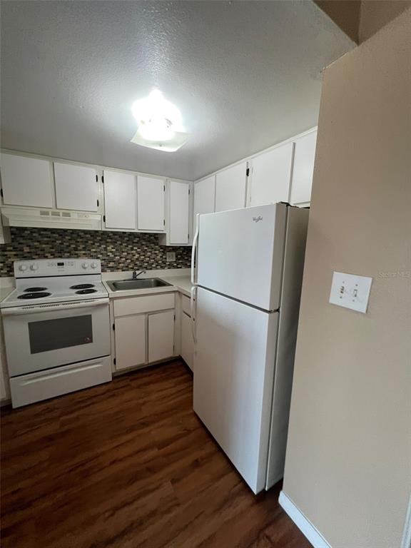 A kitchen features white cabinets, a white stove, a white refrigerator, and wood-look flooring — 618 ORANGE DRIVE UNIT 212, ALTAMONTE SPRINGS, FL