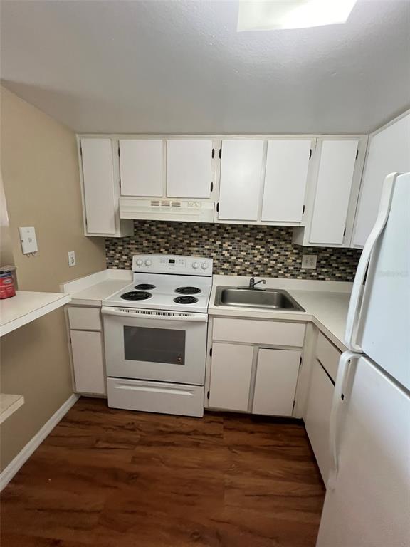 A small kitchen features white cabinets, a white electric stove, and a mosaic tile backsplash — 618 ORANGE DRIVE UNIT 212, ALTAMONTE SPRINGS, FL