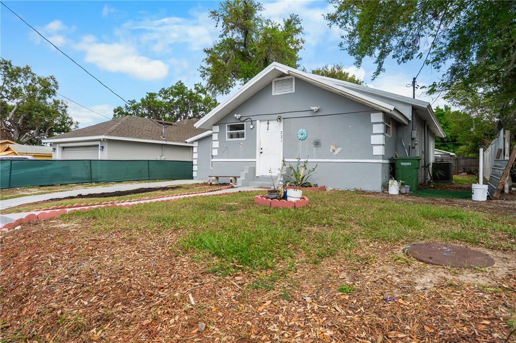 A gray, single-story house with a white door and a green trash bin outside — 221 AVENUE L NE, WINTER HAVEN, FL